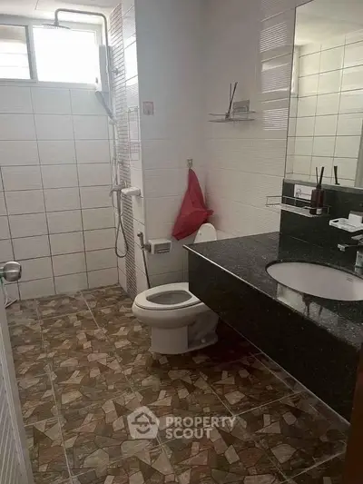 Modern bathroom with sleek black countertop and tiled flooring in a contemporary home.