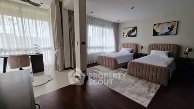 Spacious modern bedroom with twin beds and elegant decor, featuring large windows and natural light.