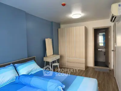 Modern bedroom with blue accents and ensuite bathroom in stylish apartment.