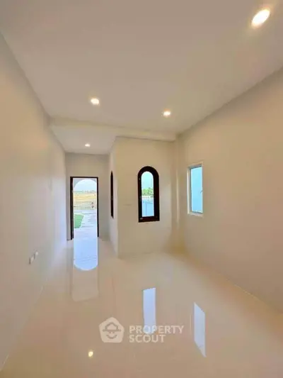 Bright empty room with glossy floors and arched windows, perfect for customization.