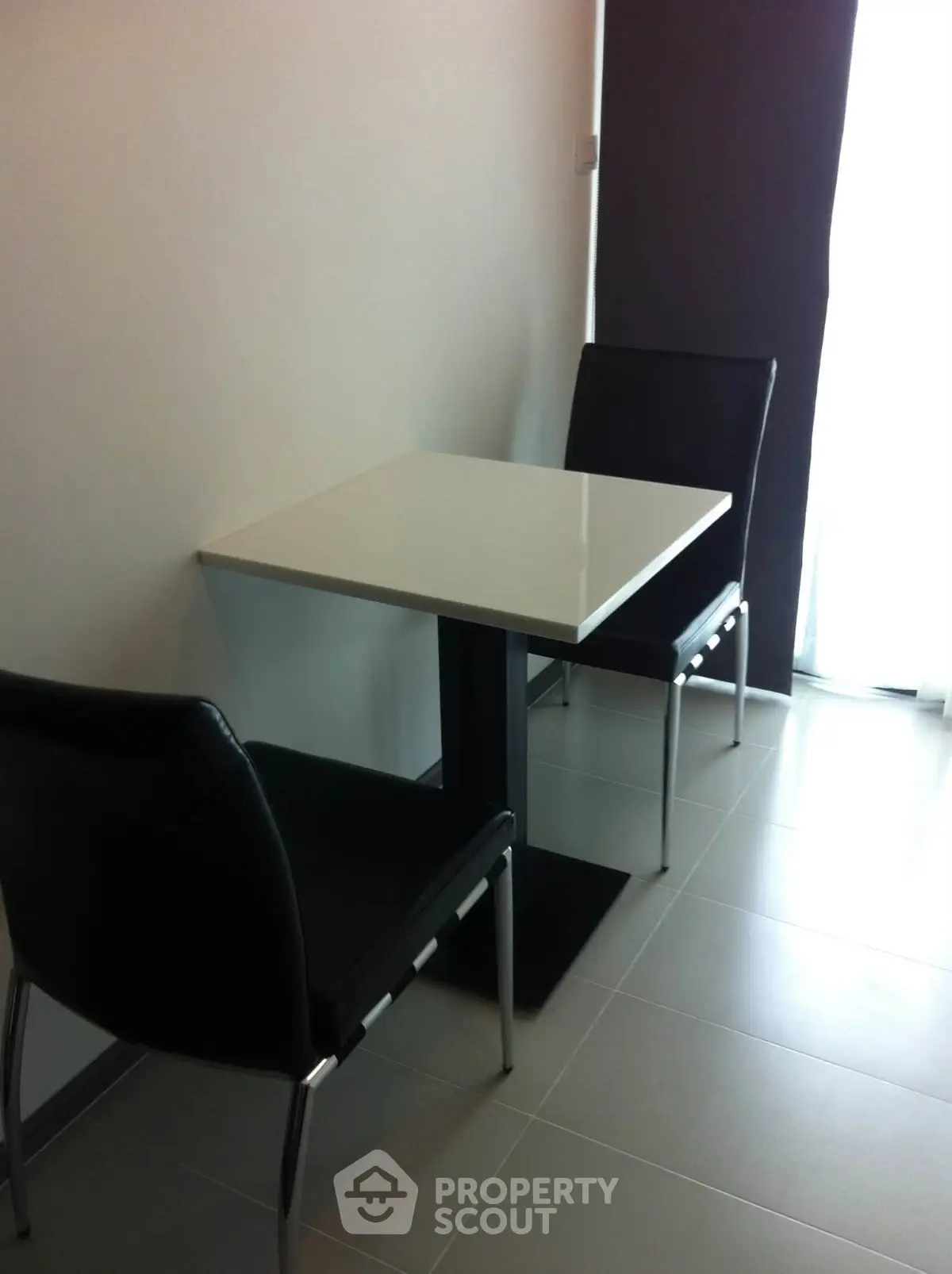 Modern minimalist dining area with sleek black chairs and a white table, perfect for compact spaces.