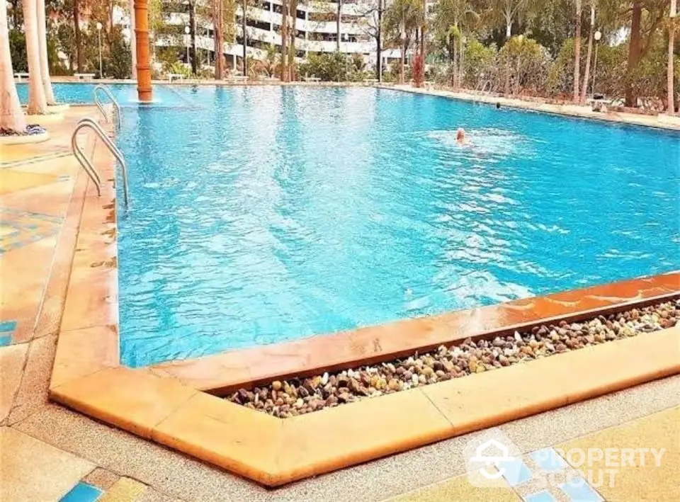 Luxurious outdoor swimming pool with lush surroundings in a premium residential complex.