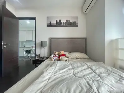 Cozy bedroom with modern decor and view into a sleek kitchen, perfect for urban living.