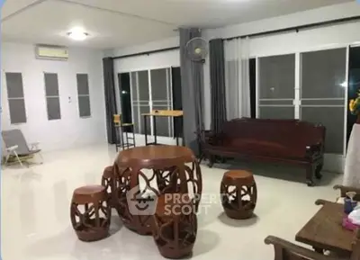 Spacious living room with elegant wooden furniture and large windows.