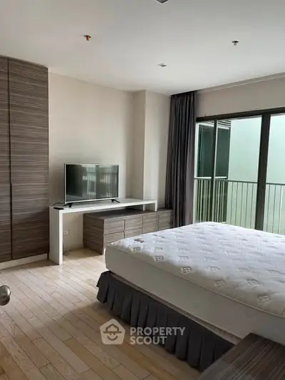 Spacious modern bedroom with balcony access and sleek furnishings.