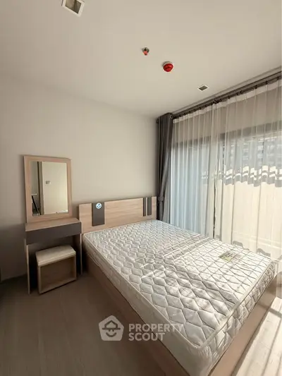 Bright bedroom with large window and modern furniture, perfect for relaxation and comfort.