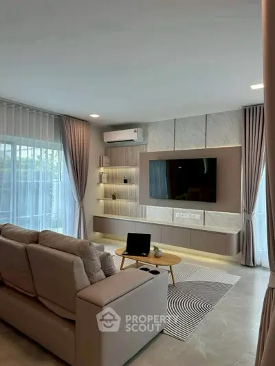 Modern living room with elegant decor and large TV, featuring cozy seating and stylish curtains.