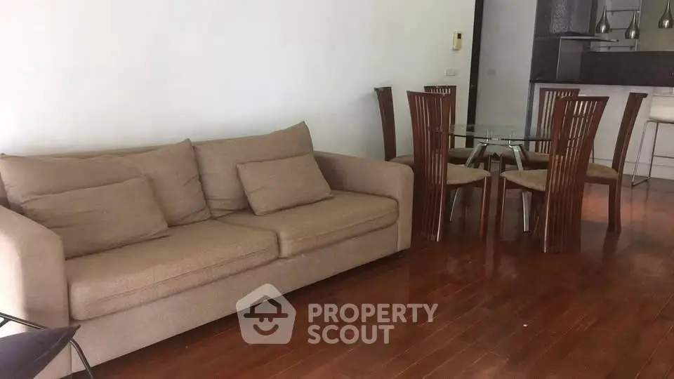 Spacious living room with modern dining area and cozy sofa on wooden flooring.