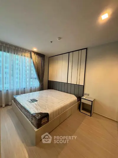 Modern bedroom with large window and stylish decor in a high-rise apartment.