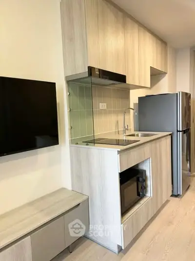 Modern compact kitchen with sleek cabinetry and stainless steel appliances in a stylish apartment.