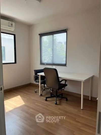 Bright study room with wooden flooring and modern furniture, ideal for productivity.