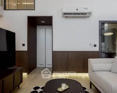 Modern living room with sleek design, featuring a wall-mounted air conditioner and stylish furniture.