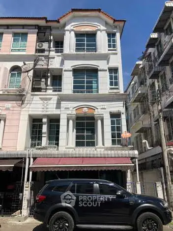 Charming multi-story residential building with elegant facade and parked SUV in urban setting.