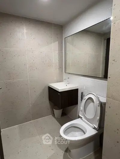 Modern bathroom with sleek fixtures and large mirror in a contemporary home.