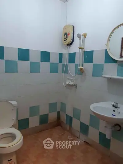 Compact bathroom with shower, toilet, and sink featuring blue and white tiles.