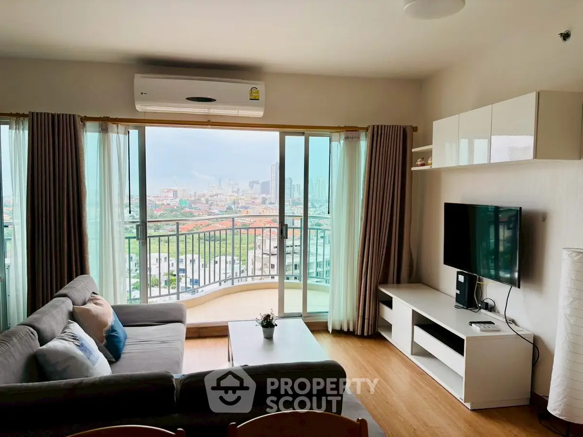 Spacious living room with balcony and city view, featuring modern furniture and natural light.