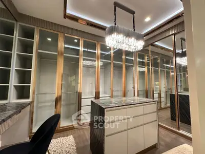 Luxurious walk-in closet with elegant chandelier and ample storage space.