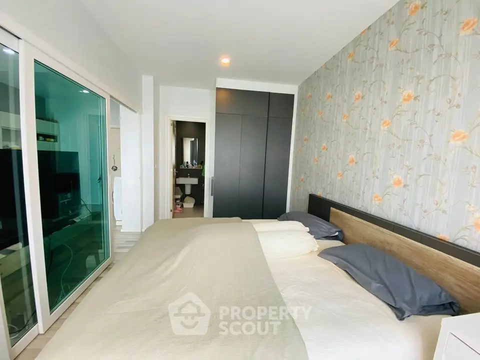 Spacious bedroom with modern decor and sliding glass doors leading to a cozy living area.