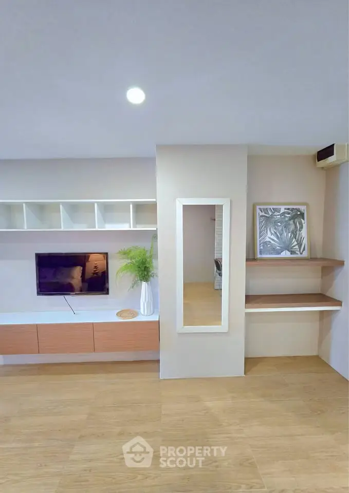 Modern living room with built-in shelves and wall-mounted TV, featuring minimalist decor.