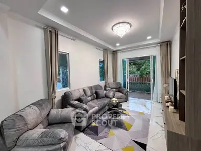 Spacious living room with modern decor and large windows overlooking greenery.