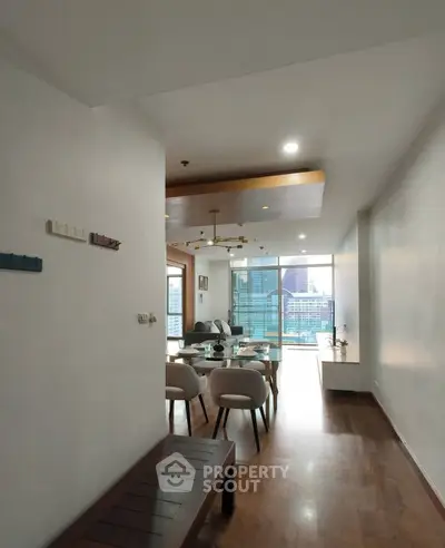 Spacious modern living room with dining area and city view, featuring elegant decor and natural light.