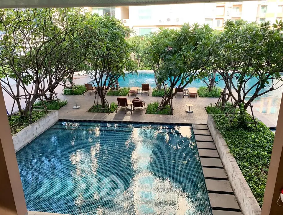 Luxurious residential pool area with lush greenery and elegant seating, perfect for relaxation and leisure.
