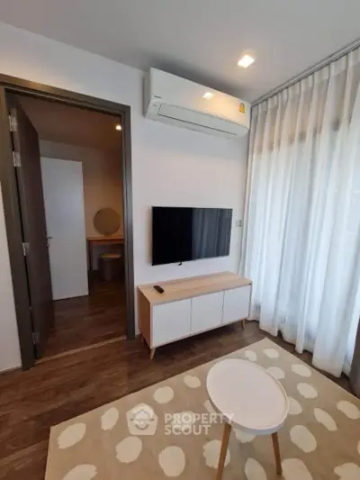 Modern living room with sleek TV setup and air conditioning, featuring stylish decor and natural light.