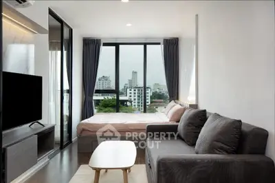 Modern studio apartment with city view, featuring cozy living area and large windows.