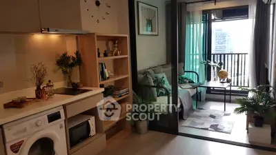 Modern apartment interior with open kitchen and cozy living area leading to a balcony with city view.