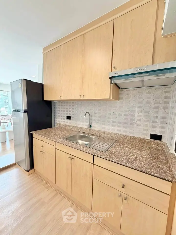 Modern kitchen with granite countertops and stainless steel appliances in a bright apartment.