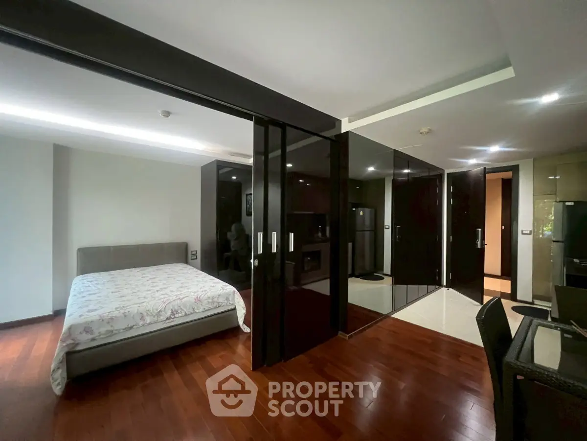 Spacious modern bedroom with wooden flooring and sleek glass partitions