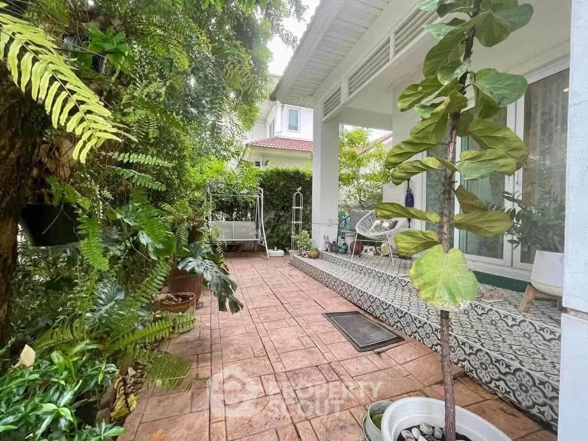 Charming garden patio with lush greenery and cozy seating area, perfect for relaxation and outdoor enjoyment.