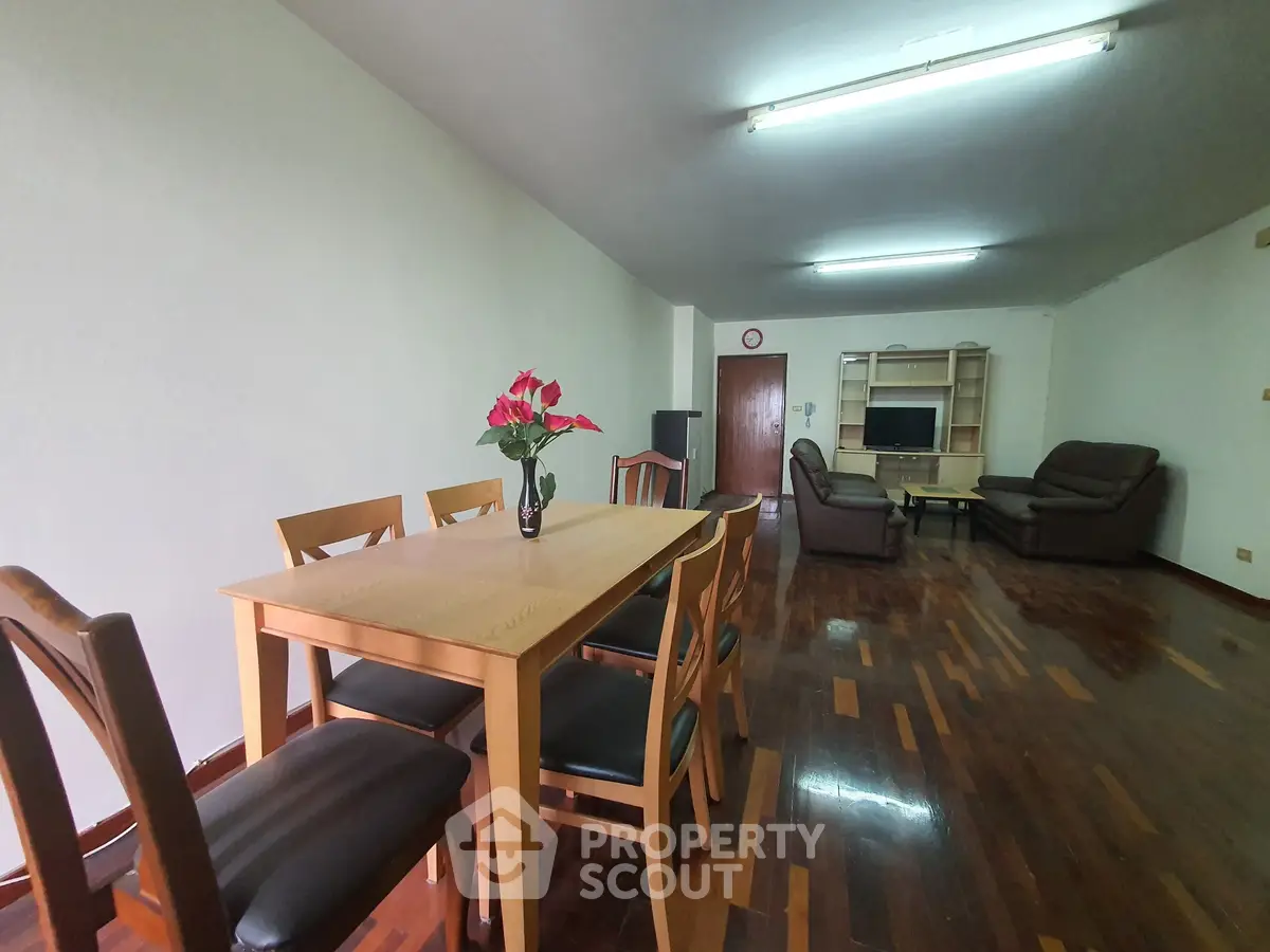 Spacious living room with wooden flooring and elegant dining set, perfect for family gatherings.
