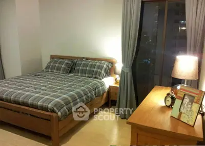 Cozy bedroom with wooden furniture and city view window, perfect for relaxation.