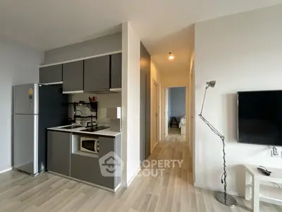 Modern apartment kitchen with sleek cabinetry and open layout, featuring a cozy hallway leading to a bedroom.