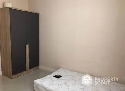 Minimalist bedroom with single bed and sleek wardrobe, ideal for compact living spaces.