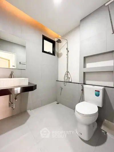 Modern bathroom with sleek fixtures and minimalist design, featuring a spacious shower area and elegant sink.