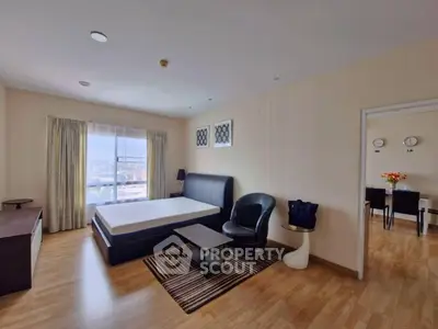 Spacious bedroom with modern furnishings and large window offering city views