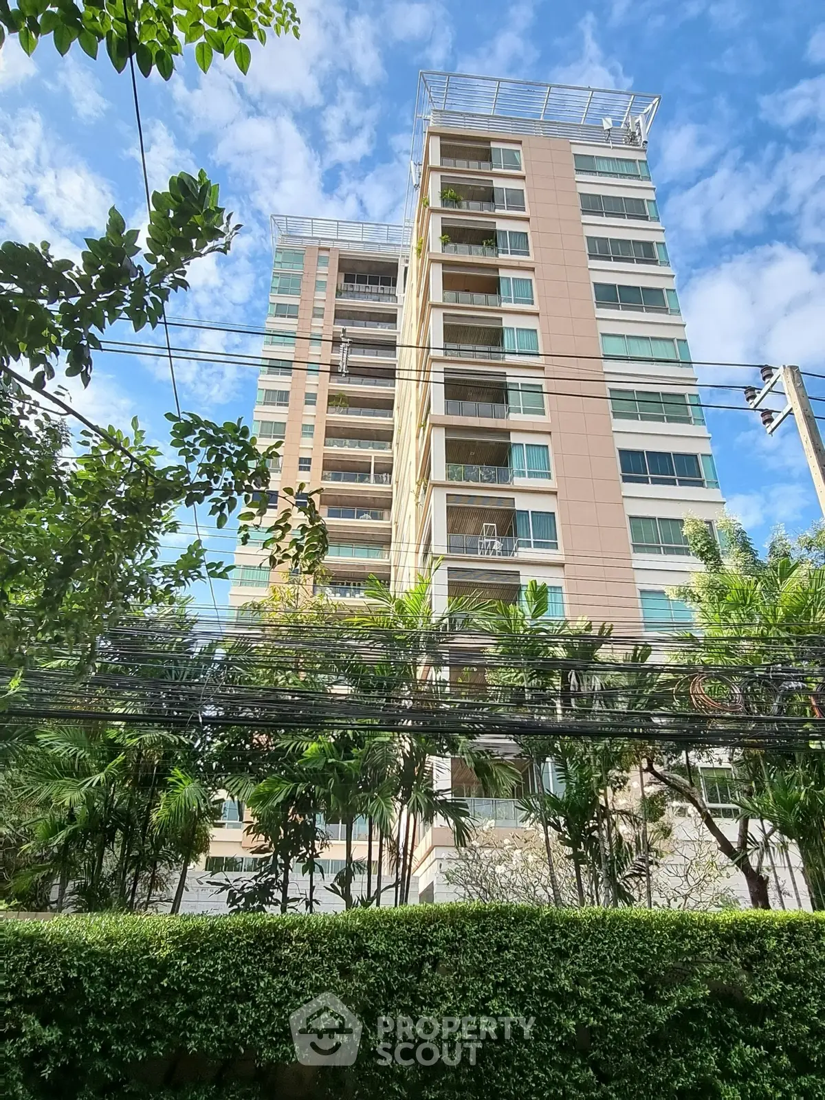 Modern high-rise building with lush greenery and clear blue sky