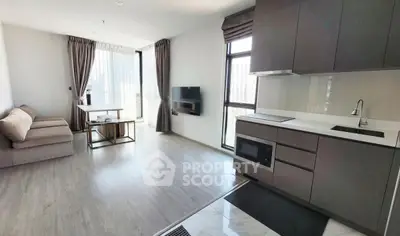 Modern open-plan living room with sleek kitchen and large windows in a high-rise apartment.