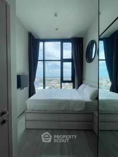 Modern bedroom with floor-to-ceiling windows offering stunning city views, featuring sleek design and ample natural light.
