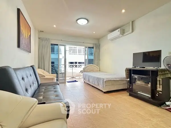Spacious living room with bed and balcony access in modern apartment.