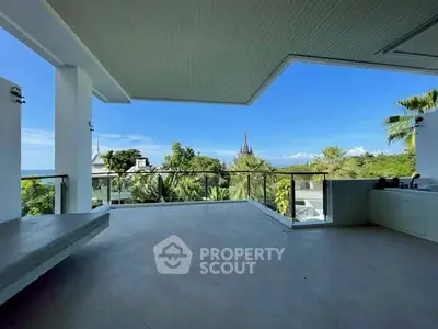 Spacious balcony with stunning view of lush greenery and distant architecture.