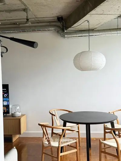Modern dining area with stylish chairs and pendant light in an industrial-style apartment.