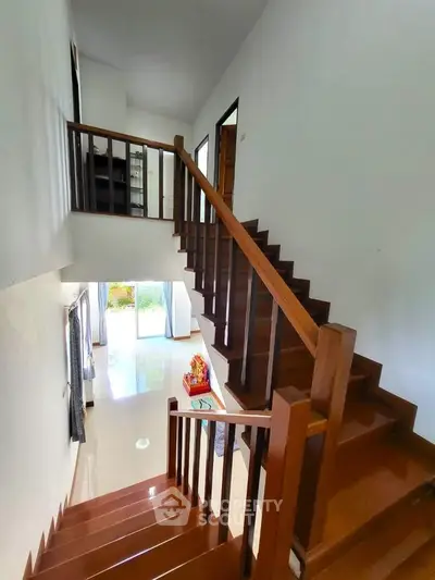 Elegant wooden staircase in a modern home with natural light and garden view.