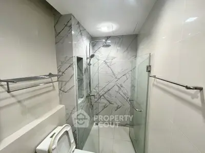 Modern bathroom with marble tiles and glass shower enclosure
