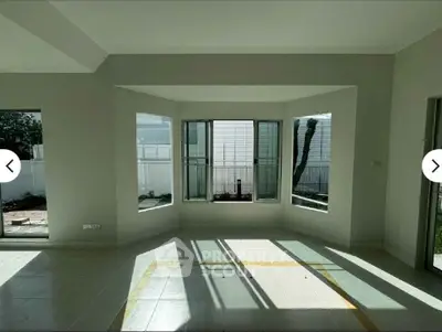 Spacious sunlit room with large windows and garden view, perfect for modern living.