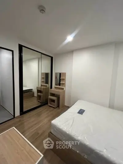 Modern bedroom with mirrored wardrobe and wooden furniture in a cozy apartment.