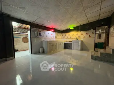 Spacious kitchen with unique ceiling design and colorful lighting, featuring a closed layout and tiled flooring.
