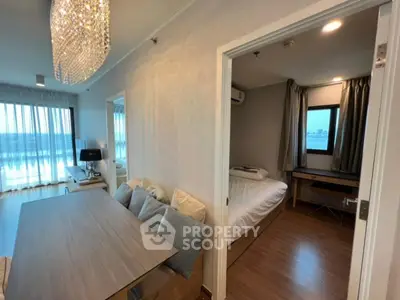 Modern apartment interior with elegant chandelier and cozy bedroom, featuring large windows and stylish decor.